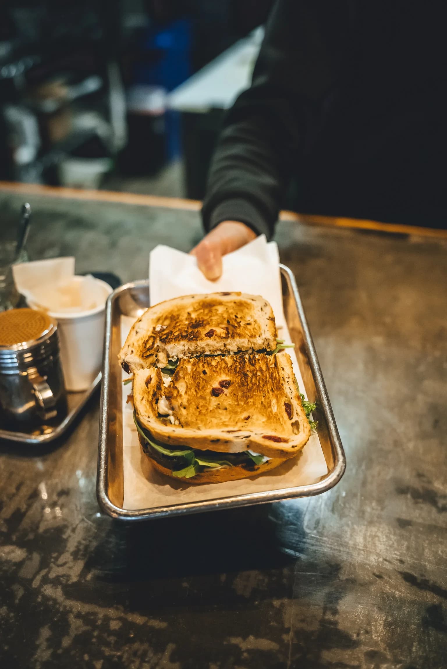 Corner Coffee barista handing off a pressed sandwich on a tray at the counter