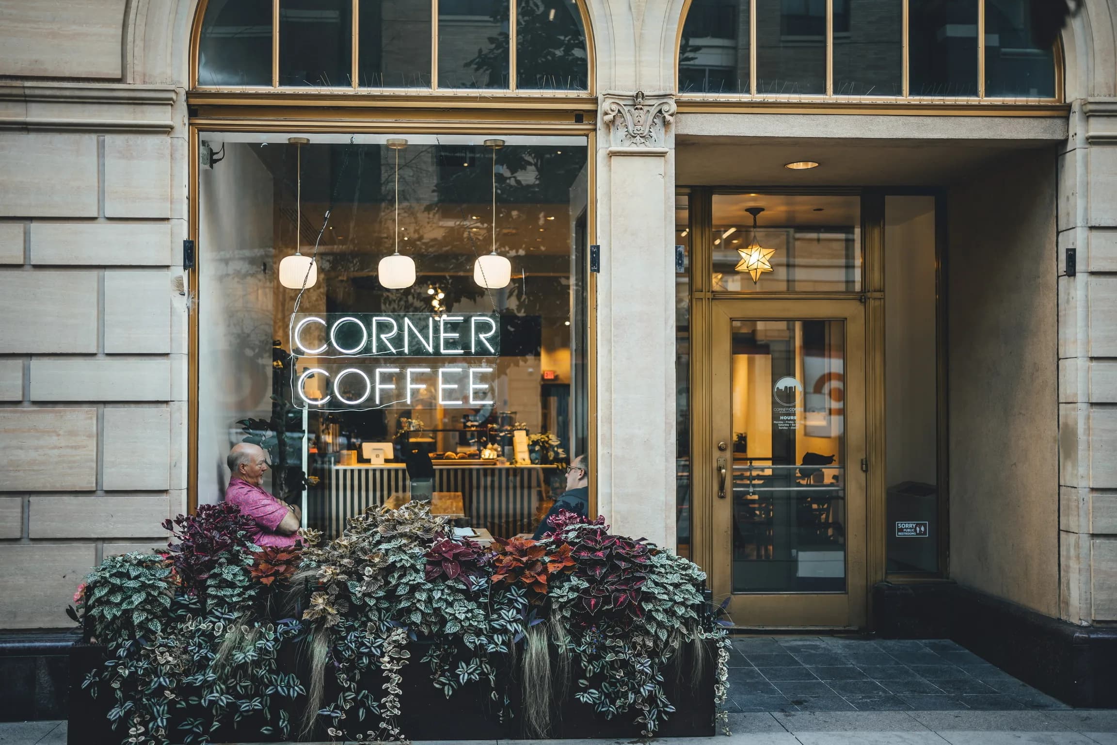 Corner Coffee Downtown storefront with neon sign and sidewalk planters